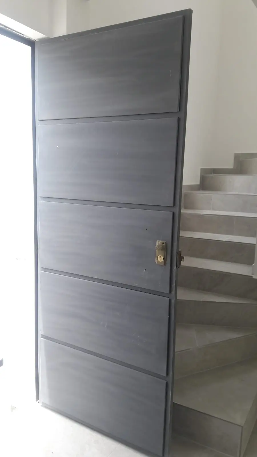 Puerta de tool gris clara con ranuras horizontales, fabricada en Quito